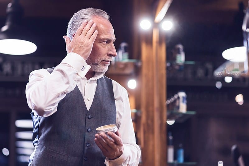 Man applies best pomade for thick hair to his hair